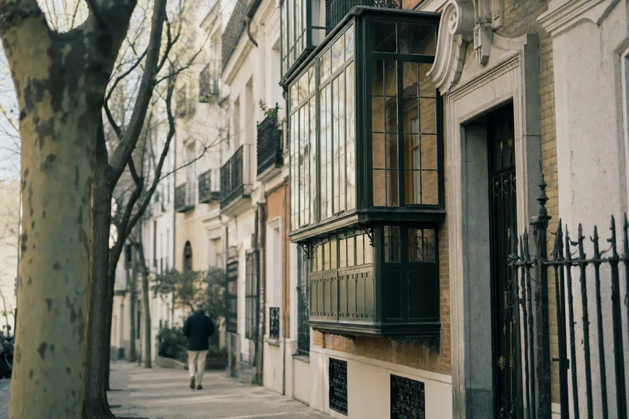 Calle de Madrid con edificios de ladrillo, miradores acristalados y plátanos