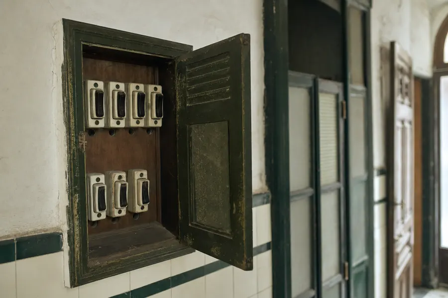 Armario de contadores eléctricos antiguo, con la puerta metálica abierta, en el portal de un edificio