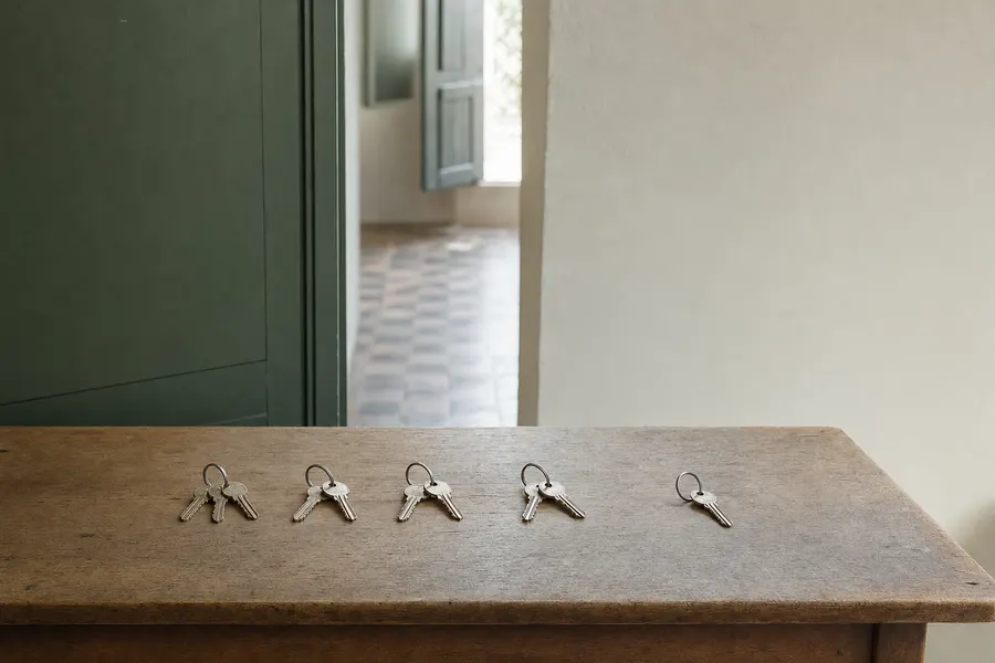 Varios juegos de llaves alineados sobre una mesa de madera, uno algo apartado