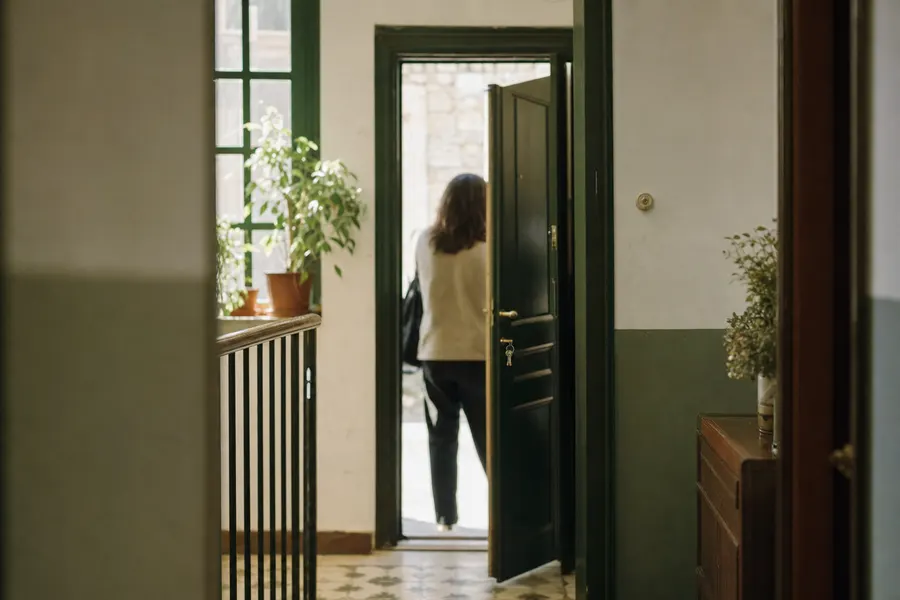 Una persona abre la puerta de su piso con las llaves puestas en la cerradura